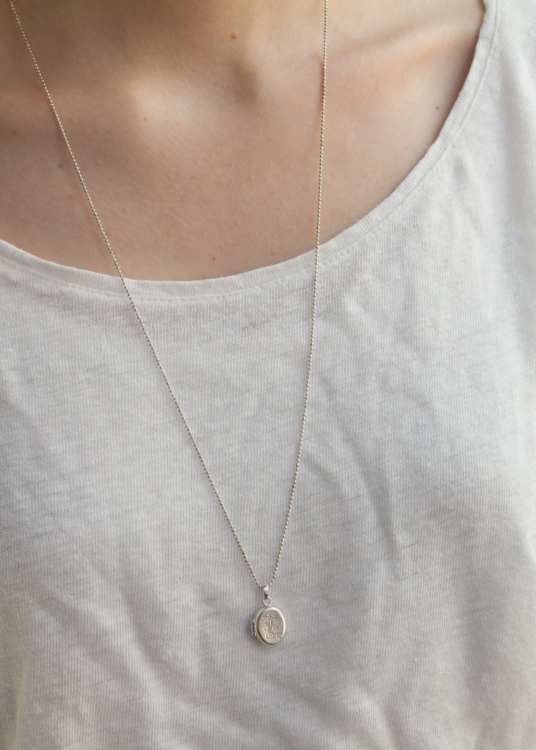 Frau trägt Medaillon mit Foto auf der Brust – elegante Silberkette